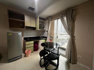 una pequeña cocina con mesa, sillas y ventana en Madison Park Apartment Near Mall Central Park, en Yakarta