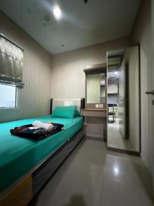 een slaapkamer met een groen bed en een spiegel bij Madison Park Apartment Near Mall Central Park in Jakarta