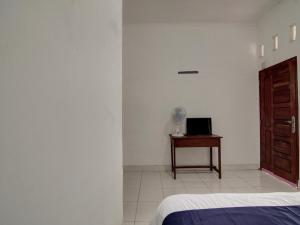 Schlafzimmer mit einem Bett und einem Tisch mit einem Ventilator in der Unterkunft SPOT ON 92635 Homestay Baiturrahmah Syariah in Pekanbaru