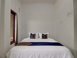 een wit bed met blauwe en witte kussens erop bij SPOT ON 92635 Homestay Baiturrahmah Syariah in Pekanbaru
