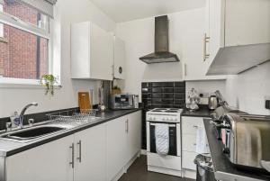a kitchen with white cabinets and a sink at Large Stylish Duplex in Central Leicester - Sleeps 8 in Leicester