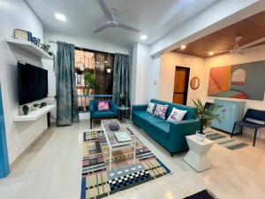 a living room with a blue couch and a table at Arc Nest, A Perfect Retreat in the Heart of Bandra by Connekt Homes in Mumbai