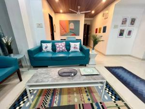 a living room with a blue couch and a table at Arc Nest, A Perfect Retreat in the Heart of Bandra by Connekt Homes in Mumbai