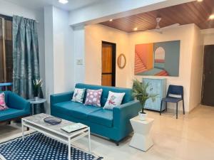 a living room with a blue couch and a table at Arc Nest, A Perfect Retreat in the Heart of Bandra by Connekt Homes in Mumbai