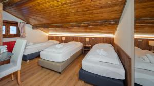 Zimmer mit 3 Betten, Tisch und Stühlen in der Unterkunft Chalet Li Mina in Livigno