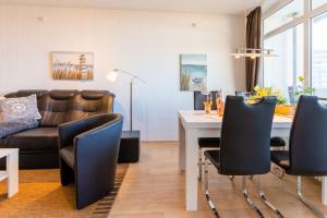 - un salon avec un canapé, une table et des chaises dans l'établissement Ferienpark - Haus O, App 0O0404, à Heiligenhafen