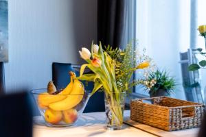 un vase en verre avec des bananes et des fleurs sur une table dans l'établissement Ferienpark - Haus O, App 0O0404, à Heiligenhafen