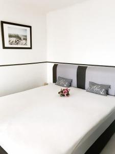 - un lit blanc avec une fleur au-dessus dans l'établissement Ferienpark - Haus O, App 0O0603, à Heiligenhafen