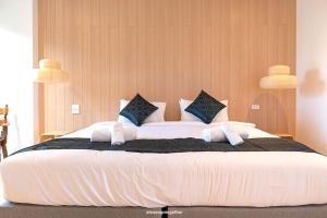- une chambre avec un grand lit blanc et des oreillers bleus dans l'établissement Pattanipirom Boutique Hotel, à Kampong Rusamileh