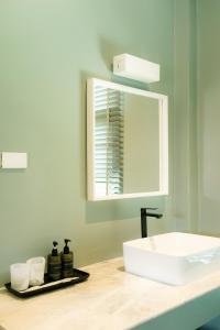 a bathroom with a white sink and a mirror at Pattanipirom Boutique Hotel in Kampong Rusamileh