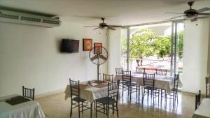a dining room with a table and chairs and a tv at Del Parque Hotel in Corozal