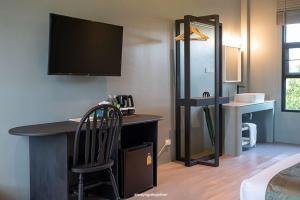 a room with a desk with a television and a chair at Pattanipirom Boutique Hotel in Kampong Rusamileh