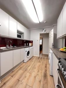 a kitchen with white cabinets and a washer and dryer at Glazebrook in London