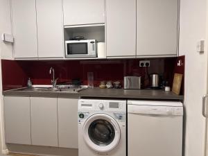 a kitchen with a washing machine and a microwave at Glazebrook in London