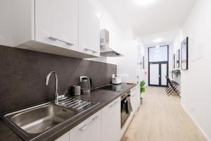 eine Küche mit weißen Schränken und einer Spüle aus Edelstahl in der Unterkunft Central City Style Rooms by Home2 in Wien
