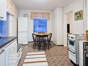 a kitchen with white appliances and a table with chairs at Mäki-mummola in Ylitornio