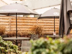 two tables with umbrellas and chairs in front of a fence at ibis Paris Porte D'Orleans in Montrouge