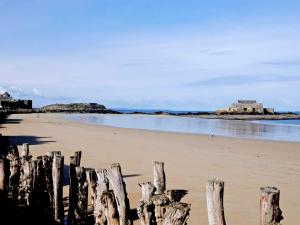 une plage avec une clôture en bois dans le sable dans l'établissement ibis Saint Malo Plage, à Saint-Malo