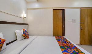 a bedroom with a bed and a wooden door at FabExpress Prabhu Sharan in Mumbai