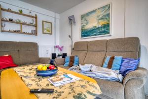 ein Wohnzimmer mit einem Sofa und einem Tisch mit einer Obstschale in der Unterkunft Haus am See, App 3HAS06 in Heiligenhafen