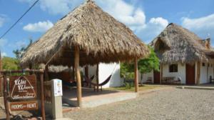 un edificio con una cabaña de paja con una señal en Wild Waves Surf-House en Popoyo