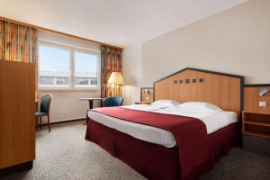 una camera d'albergo con un grande letto e una finestra di Ramada by Wyndham Bottrop City a Bottrop