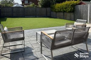a patio with two chairs and a table and a lawn at Modern 2 Bed House With Driveway in Longton