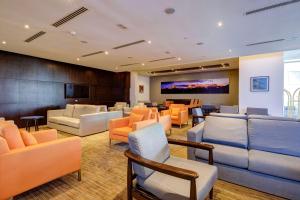 een wachtkamer met banken en stoelen en een televisie bij La Quinta by Wyndham Santiago Aeropuerto in Santiago