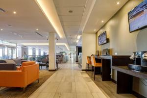 an office lobby with orange chairs and a bar at La Quinta by Wyndham Santiago Aeropuerto in Santiago