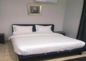 uma cama com lençóis brancos e almofadas num quarto em نجمة حراء للشقق المفروشة em Jidá