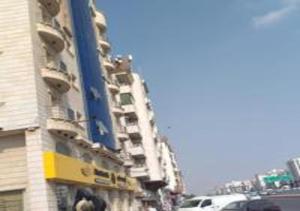 um edifício alto com carros estacionados em frente em نجمة حراء للشقق المفروشة em Jidá