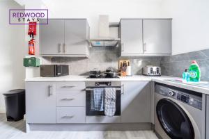a kitchen with a washer and a washing machine at Quality Serviced Apartments in Aldershot Town Centre, Free WiFi By Redwood Stays in Aldershot