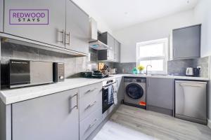 een keuken met witte kasten en een wasmachine en droger bij Quality Serviced Apartments in Aldershot Town Centre, Free WiFi By Redwood Stays in Aldershot