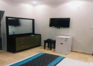 uma sala de estar com uma televisão, uma cómoda e um espelho em نجمة حراء للشقق المفروشة em Jidá