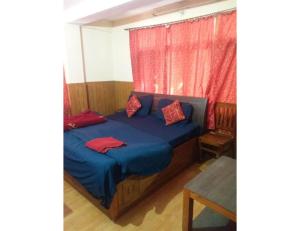a bedroom with a bed with blue sheets and red pillows at Chandel Home Stay , Shimla in Shimla