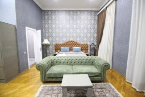a living room with a green couch and a bed at Pilot Baku hotel in Baku