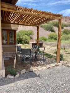 eine Terrasse mit einem Tisch und Stühlen unter einer hölzernen Pergola in der Unterkunft La Nochera in Tilcara