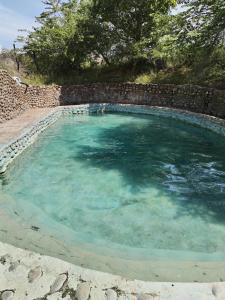une grande piscine d'eau avec un mur en pierre dans l'établissement biohotel tatacoa Qji, à Villavieja