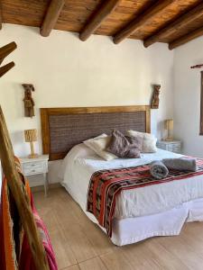 a bedroom with a large bed with a wooden headboard at La Nochera in Tilcara