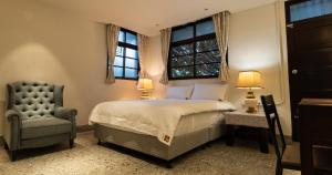 um quarto com uma cama, uma cadeira e 2 janelas em 文坊 Wen Guest House em Taipei