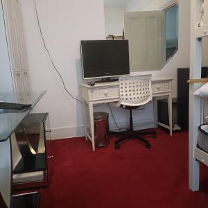 a computer desk with a monitor and a chair at Alys apartment in London