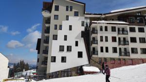 two people skiing in the snow in front of a building at Стената 4-3А in Pamporovo