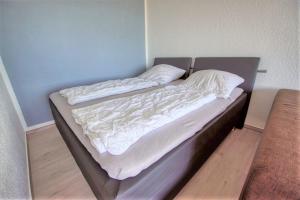 een ongeëvenaard bed in een slaapkamer met een blauwe muur bij Haus Hanseatic, App 2SC104 in Heiligenhafen