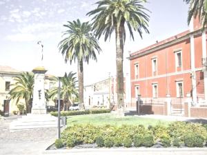 a courtyard with palm trees and a building at ITALIA GUESTHOUSe in Milis