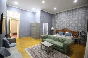 Pilot Baku hotel في باكو: غرفة نوم مع أريكة خضراء وسرير وطاولة