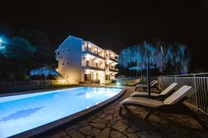a swimming pool at night with two chairs and umbrellas at Giorgos apartments in Dassia