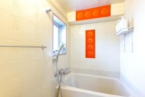 ein weißes Badezimmer mit Badewanne und Fenster in der Unterkunft Geisha Expelience Stay in Tokio