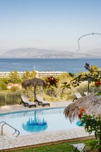 a swimming pool with chairs and the ocean in the background at Giorgos apartments in Dassia