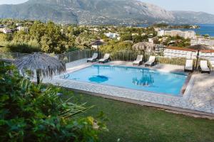 a swimming pool with chairs and a view of the ocean at Giorgos apartments in Dassia