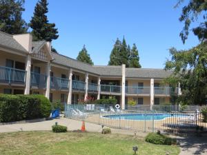 a large building with a swimming pool in the courtyard at Days Inn by Wyndham Redwood City in Redwood City